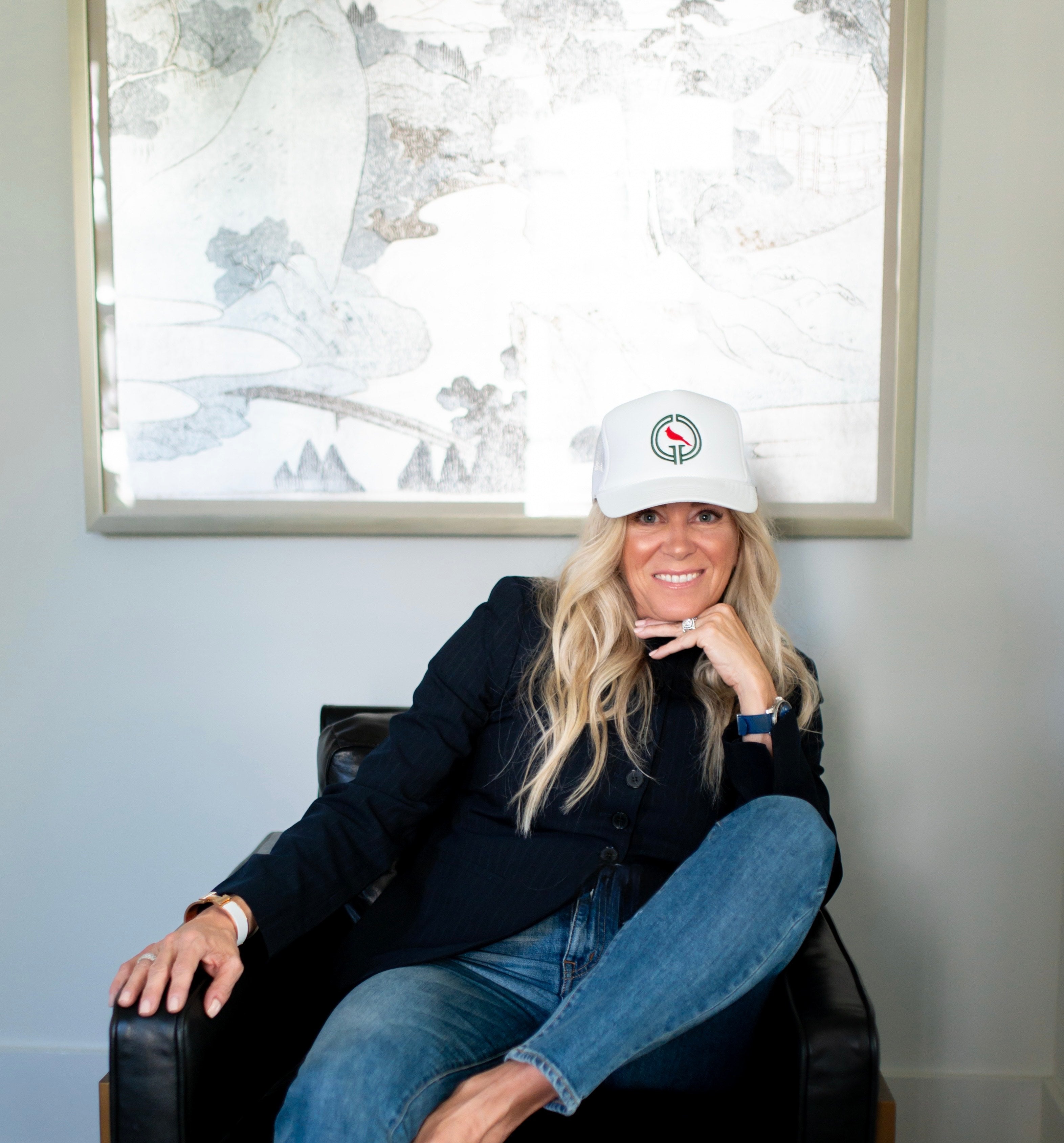Woman sitting in a chair wearing a Good Girl Golf hat.