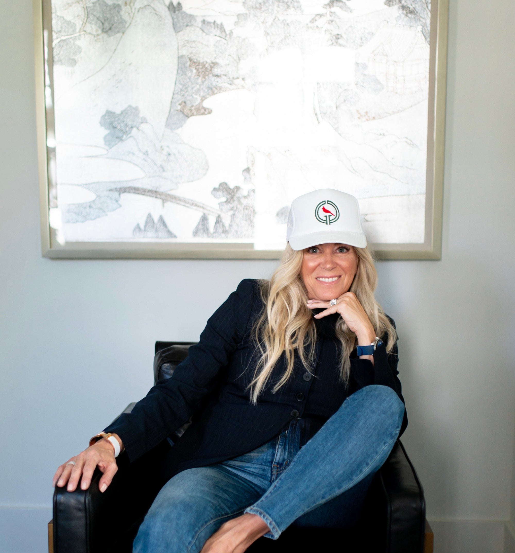 Woman sitting in a chair wearing a Good Girl Golf hat.